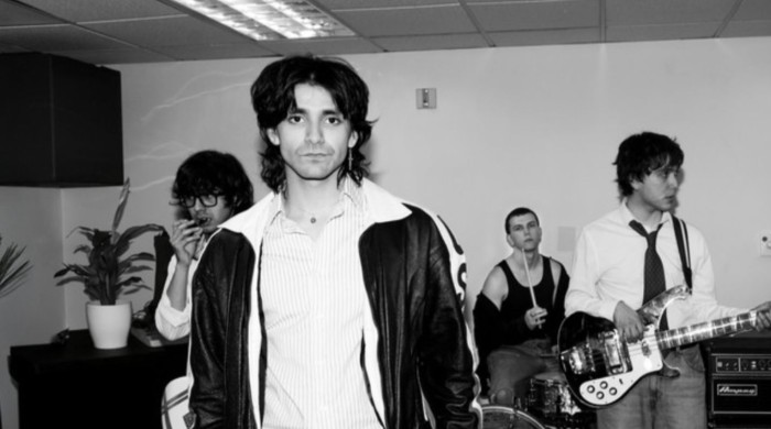 four men stand in a band practice room
